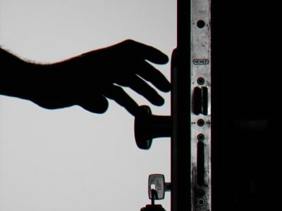 silhouette photo of person holding door knob